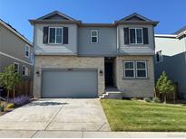Two-story home featuring stone and gray siding, a two-car garage, well-manicured lawn, and tasteful landscaping at 16651 W 93Rd Ave, Arvada, CO 80007