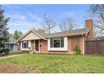 Charming brick home featuring manicured lawn, mature trees, and detailed architectural elements under a bright, partly cloudy sky at 1100 Pontiac St, Denver, CO 80220