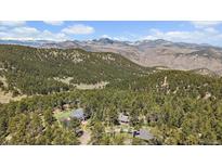 Scenic aerial view of mountain home nestled among trees with mountain range in the background at 513 Mt Blue Sky Rd, Golden, CO 80401