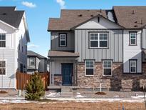Beautiful townhome with stone accents, gray siding, a blue front door, and a well-maintained lawn at 249 Mayfly Ln, Berthoud, CO 80513