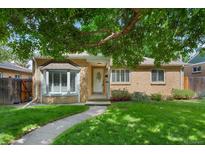 Charming brick home with bay window, lush lawn, and mature tree providing shade at 1080 S Garfield St, Denver, CO 80209