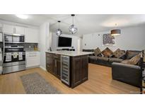 Open-concept living room featuring a kitchen island with a built-in wine cooler and comfortable leather seating at 1260 York St # 102, Denver, CO 80206