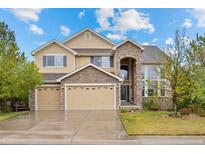 Inviting two-story home featuring a stone archway, three-car garage, and mature landscaping at 5791 Chisholm Pl, Parker, CO 80134