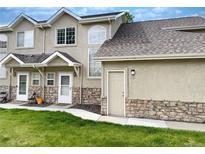 Charming townhome featuring a stone facade, well-maintained lawn, and inviting entrance, offering a welcoming curb appeal at 2247 Coronado Pkwy N #D, Denver, CO 80229