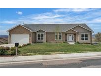 Charming brick home features a manicured lawn, a two-car garage, and lovely landscaping at 6839 Estes Dr, Arvada, CO 80004