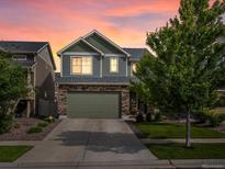 Two-story home featuring stone accents, an attached two-car garage, and professionally landscaped yard during a colorful sunset at 5358 Ventura St, Denver, CO 80249