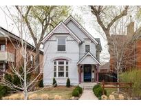 Charming two-story home featuring a painted brick facade, landscaped yard, and eye-catching trim details at 2808 N Humboldt St, Denver, CO 80205