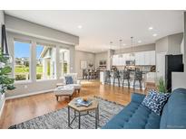 Bright living room with hardwood floors, large windows, and open floor plan to the kitchen and dining area at 14284 W 88Th Dr # B, Arvada, CO 80005