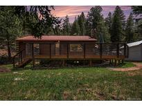 Charming log cabin with a spacious deck surrounded by lush greenery and a beautiful sunset at 11080 S Deer Creek Rd, Littleton, CO 80127