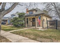 Charming single-story home featuring a cozy front porch, well-maintained lawn, and an American flag at 3064 S Cherokee St, Englewood, CO 80110