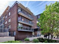 Multi-story brick building with multiple balconies in an urban area under a clear blue sky at 830 N Sherman St # 205, Denver, CO 80203