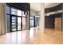 Spacious living room features large windows, balcony, and hardwood floors, offering modern urban living at 3100 Huron St # 4N, Denver, CO 80202