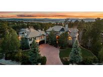 A stunning home with an expansive driveway surrounded by lush landscaping and mature trees at 5085 Knobcone Dr, Castle Rock, CO 80108