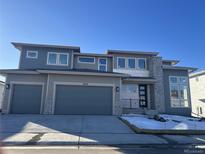 Two-story modern home with gray siding, three-car garage, and stone accents at 4926 Coal Bank Dr, Castle Rock, CO 80104