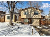 Ranch style home with brick accents and a two-car garage, nestled on a tree-lined street at 8653 W 67Th Ave, Arvada, CO 80004