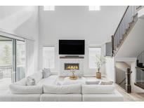 Bright living room with high ceilings, a modern fireplace, and a staircase with metal railing at 27500 E Lakeview Dr, Aurora, CO 80016
