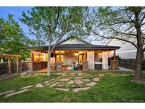 Inviting covered patio with outdoor kitchen, seating area, hot tub, and lush landscaping, ideal for relaxing and entertaining at 6480 Moss Cir, Arvada, CO 80007
