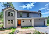 Two-story home with gray siding, complemented by an attached garage and colorful front door at 6904 Sprucedale Pkwy, Evergreen, CO 80439