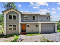 Charming two-story home featuring a well-manicured lawn, complemented by an attached two car garage at 6904 Sprucedale Pkwy, Evergreen, CO 80439