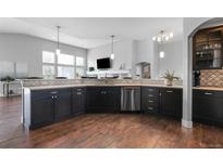 Modern kitchen features stainless steel appliances, dark cabinetry, and hardwood floors at 9060 Ferncrest St, Firestone, CO 80504