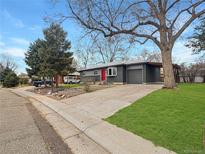 Charming gray home featuring a red front door, attached garage, mature trees, and a well-maintained front lawn at 9639 W 63Rd Pl, Arvada, CO 80004