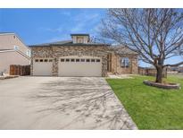 Charming brick home featuring a three-car garage, landscaped lawn, and mature trees at 5977 Sparrow Ave, Firestone, CO 80504