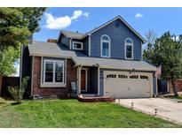 Charming two-story home boasts a brick and blue siding exterior and well-manicured front lawn at 8680 Apache Plume Dr, Parker, CO 80134