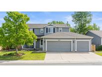 Charming two-story home with a three-car garage, well-maintained lawn, and mature shade trees on a sunny day at 5434 S Rome St, Aurora, CO 80015