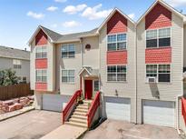 Three-story townhome featuring a red staircase leading up to a red front door and a one-car garage at 114 Vale St, Palmer Lake, CO 80133