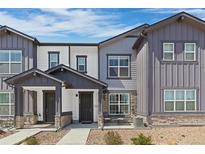 Charming townhome featuring a covered entryway, stone accents, and manicured landscaping at 132 Ambrose St, Erie, CO 80516