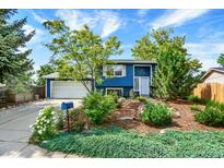 Charming two-story blue home with lush landscaping, mature trees, and an attached two-car garage at 13496 Alcott Way, Broomfield, CO 80020