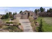 Inviting two-story home featuring a three-car garage, manicured lawn, and beautiful landscaping at 6398 Lost Canyon Ranch Rd, Castle Rock, CO 80104