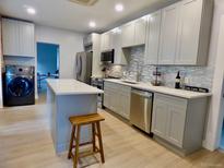 Modern kitchen features grey cabinets, stainless appliances, backsplash, and a center island with seating at 2737 N Marion St, Denver, CO 80205