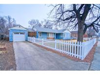 Ranch style home with blue siding, white picket fence, and attached garage at 202 9Th Ave, Longmont, CO 80501