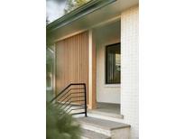 Inviting front porch with modern wood slat wall and stylish black railing adds curb appeal to the entrance at 4631 Zuni St, Denver, CO 80211