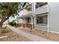 Charming townhome featuring a covered porch with brick accents and well-maintained landscaping at 12935 Lafayette St # B, Thornton, CO 80241