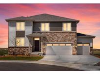 Charming two-story home boasts a stone facade and three-car garage, illuminated by a vibrant sunset at 1965 S Coolidge Way, Aurora, CO 80018