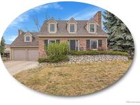 Charming brick home featuring a manicured front lawn and an attached two car garage at 7426 S Hudson Way, Centennial, CO 80122