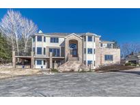 Elegant two-story home boasting a brick facade, balcony, and impressive entrance, set against a clear blue sky at 7672 S Ensenada Ct, Centennial, CO 80016