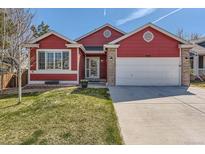 Charming red home with a well-maintained lawn, two-car garage and brick-accented entryway at 9408 High Cliffe St, Highlands Ranch, CO 80129