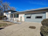 Single-story home featuring a convenient access ramp and attached gray garage at 15003 Olmsted Dr, Denver, CO 80239