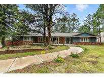 Charming home featuring blue siding, brick accents, a welcoming porch, and mature trees at 19070 White Fawn Dr, Monument, CO 80132
