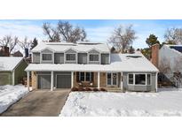 Charming two-story home featuring a well-maintained lawn and attached two car garage and snow covered roof at 10703 W Turtle Mtn, Littleton, CO 80127