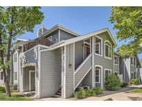 Inviting two-story condo with gray siding, red door, staircase entrance, and fresh green landscaping at 8500 E Jefferson # 3C, Denver, CO 80237