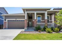 Brick ranch home with front porch and landscaped lawn at 26774 E Archer Ave, Aurora, CO 80018