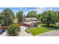 Stunning two-story home with a three-car garage, mature trees, and lush green lawn at 11796 W 53Rd Pl, Arvada, CO 80002