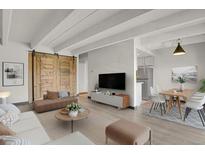 Bright living room featuring modern furniture, wood floors, a decorative sliding barn door, and an open concept to the kitchen at 100 S Clarkson St # 303, Denver, CO 80209