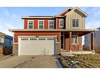 Two-story home featuring a two-car garage and a red and gray exterior at 3520 Little Bell Dr, Frederick, CO 80516