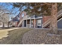 View of a two-story condo featuring brick and wood siding, and an outside staircase on a sunny day at 14308 E Whitaker Pl # 114, Aurora, CO 80015