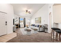 Bright living room featuring vaulted ceilings, a cozy fireplace, neutral carpet, and lots of natural light at 5756 N Genoa Way # 12-305, Aurora, CO 80019